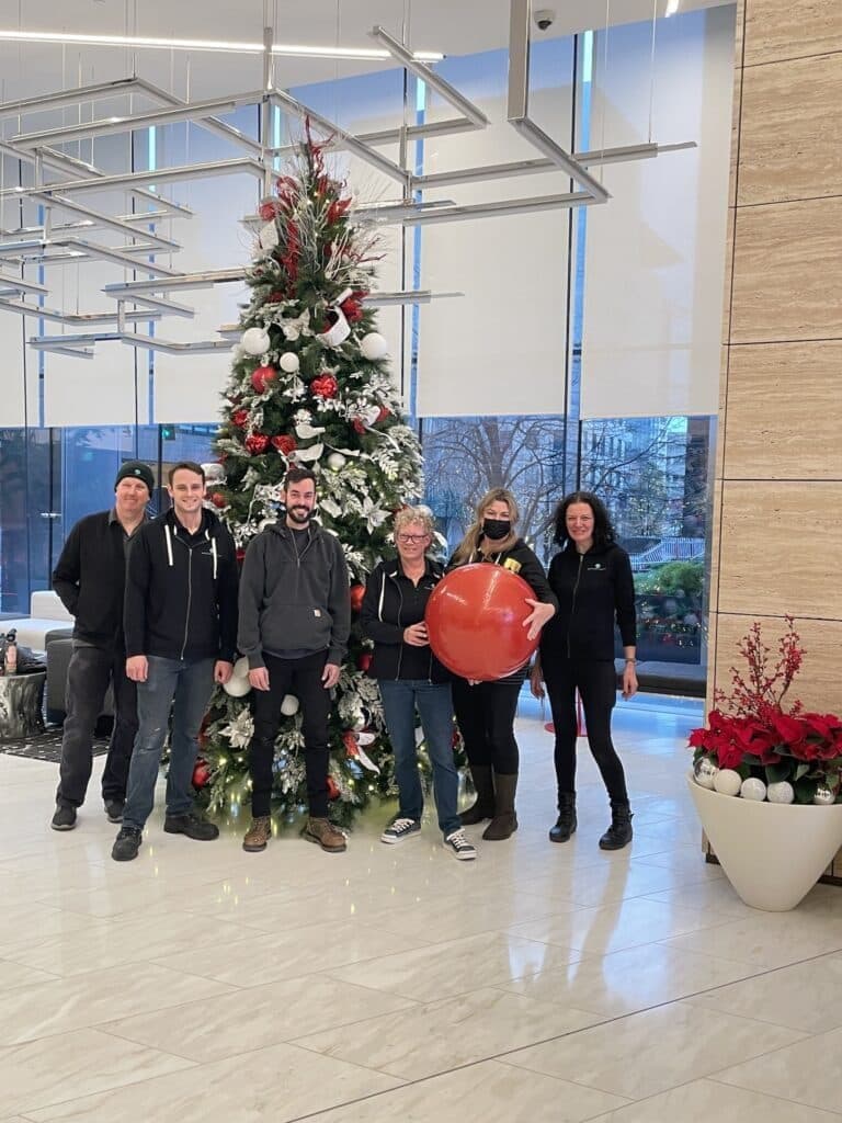 The team gathered around a decorated holiday tree after completing a seasonal installation.